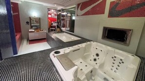 A modern bathroom with a large bathtub, a mirror, and a tiled wall with a Nike logo. - No9 Hotel (Changhua)