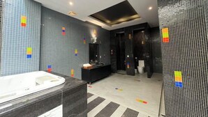 A modern bathroom with a large bathtub, a black vanity, and a shower area. - No9 Hotel (Changhua)