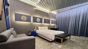 A modern bedroom with a bed, a sofa, a small table, and a blue trash bin. - No9 Hotel (Changhua)