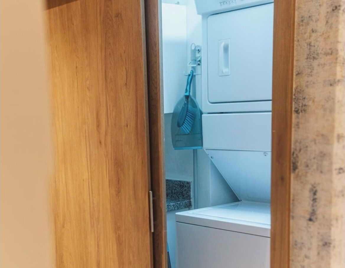 Une buanderie équipée d’un lave-linge et d’un sèche-linge, d’une serpillière bleue et d’un mur carrelé.