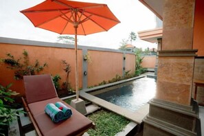 A poolside area with a lounge chair, an umbrella, and a small pool. - Moning Villa Ubud (Bali)