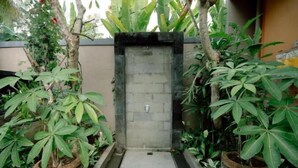 A narrow pathway leading to a door framed by plants and a stone wall. - Moning Villa Ubud (Bali)