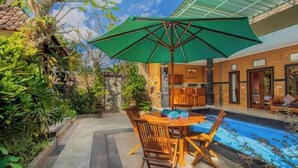An outdoor dining area with a table, chairs, and a green umbrella. - Moning Villa Ubud (Bali)