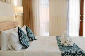A hotel room with a bed, pillows, a blanket, a towel, and a window with curtains. - Moning Villa Ubud (Bali)