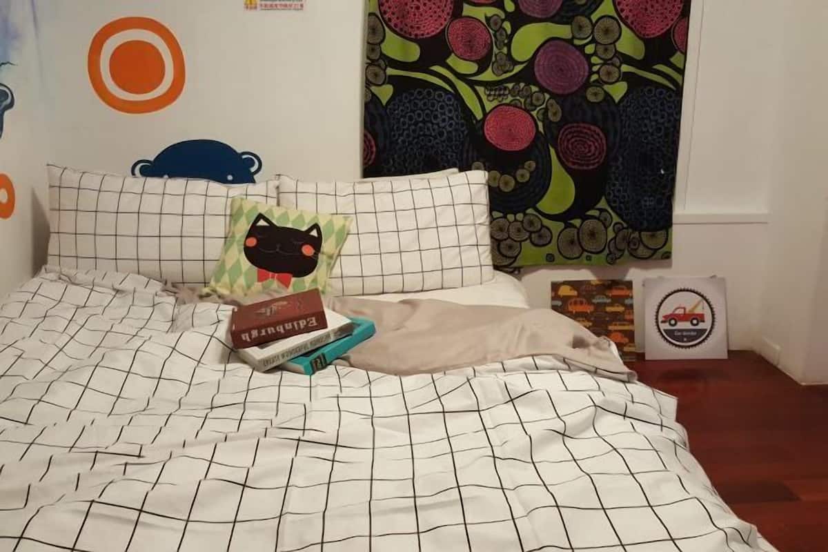 Un llit amb un estovat estampat, almoines i una manta. Hi ha llibres i una almoina amb un personatge de dibuix animat al llit.