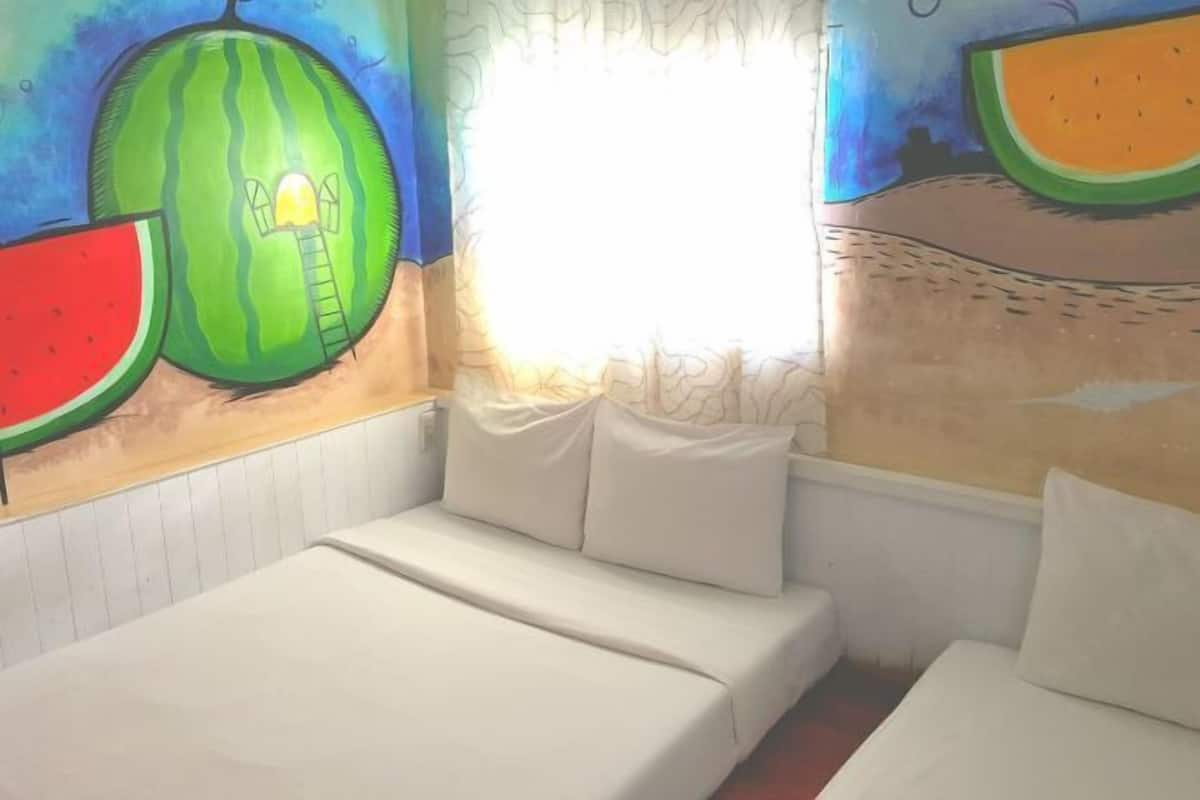Habitació amb un llit, una finestra amb cortines i un mural de fruita a la paret.