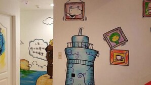 A wall with a large, colorful lighthouse drawing and framed pictures. - Mr.Rabbit (Pingtung)