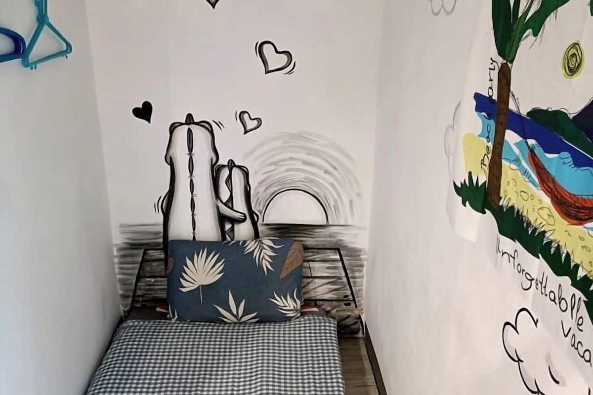 Un dormitori amb llit, almoines i un mural a la paret.