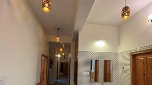 A hallway with a wooden cabinet and sink, patterned wall, and pendant lights. - Hotel Himalayan Park (Aut)