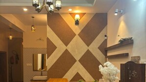 A reception area with a wooden counter, a chandelier, and a wall with a geometric pattern. - Hotel Himalayan Park (Aut)