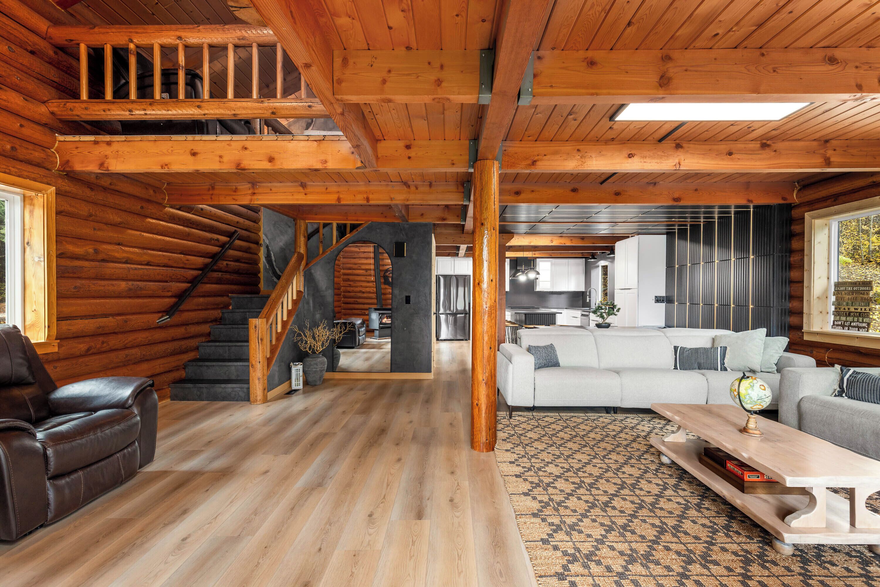 A spacious living area with a wooden staircase, a sofa set, and a dining table.