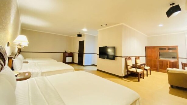 A hotel room with two beds, a TV, a wooden cabinet, and a sofa. - Fu Bao Motel (Hualien)