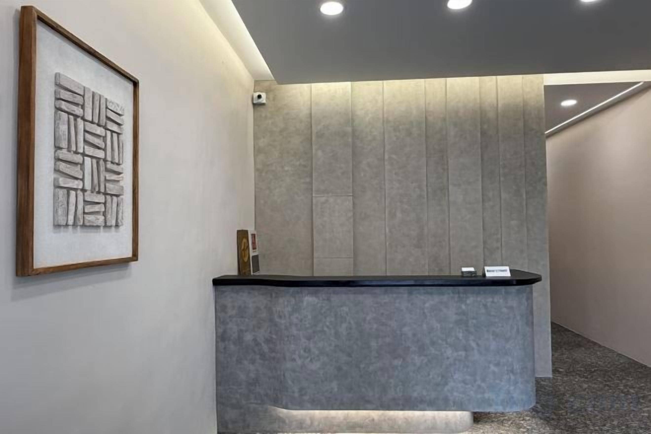 A reception desk with a grey countertop, a framed abstract artwork on the wall, and a modern interior design.