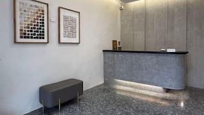 Een receptie met een marmeren vloer, een receptiebalie en twee ingelijste abstracte kunstwerken aan de muur.