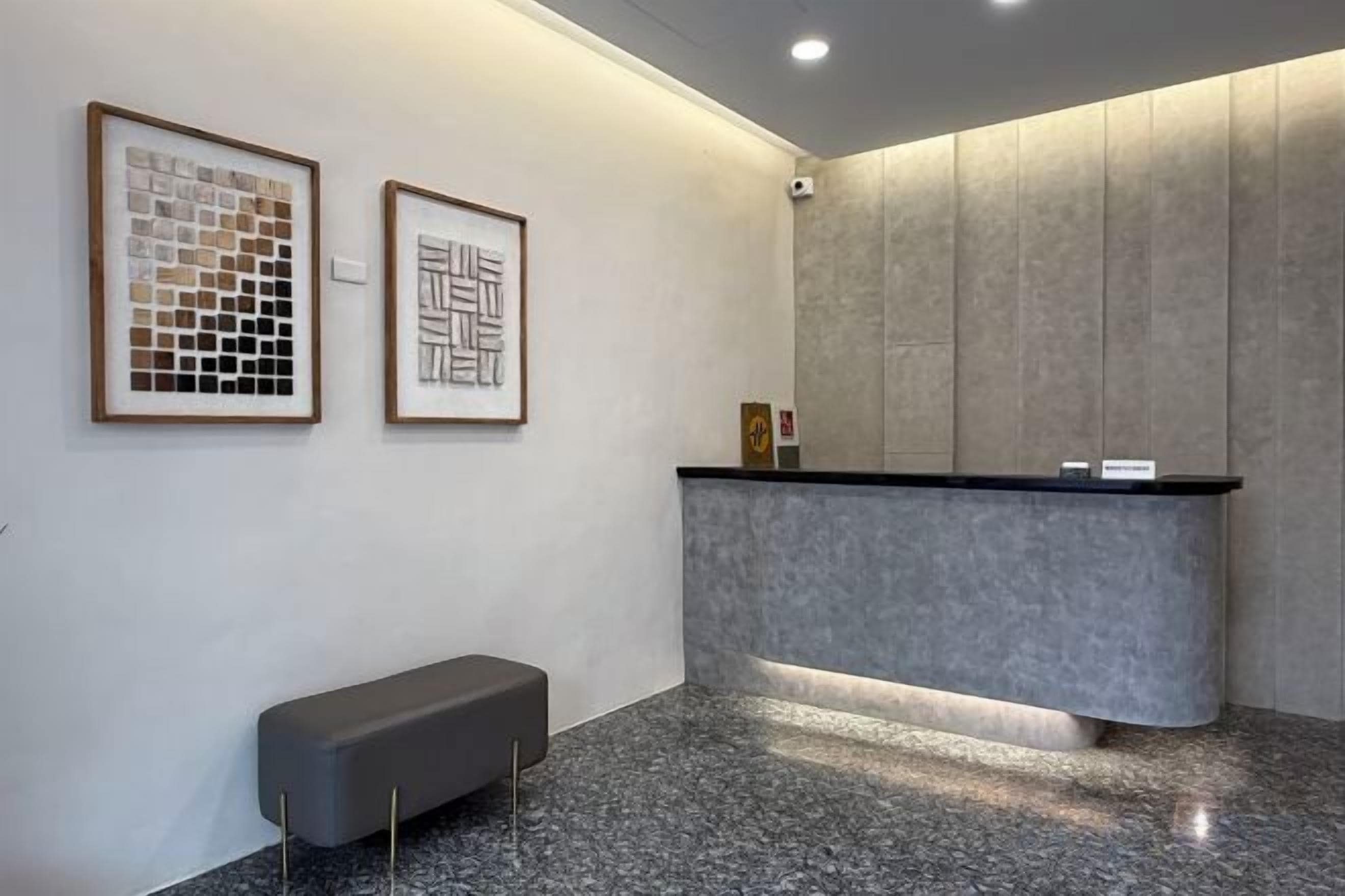 Un área de recepción con mostrador, obras de arte enmarcadas en la pared y un banco.