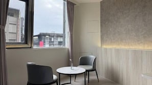 Een moderne kamer met een groot raam, twee stoelen, een tafeltje en een structuurwand.