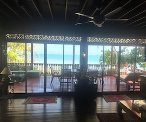 Ein Zimmer mit Meerblick, einem Deckenventilator und einer Sitzecke mit Tisch und Stühlen.