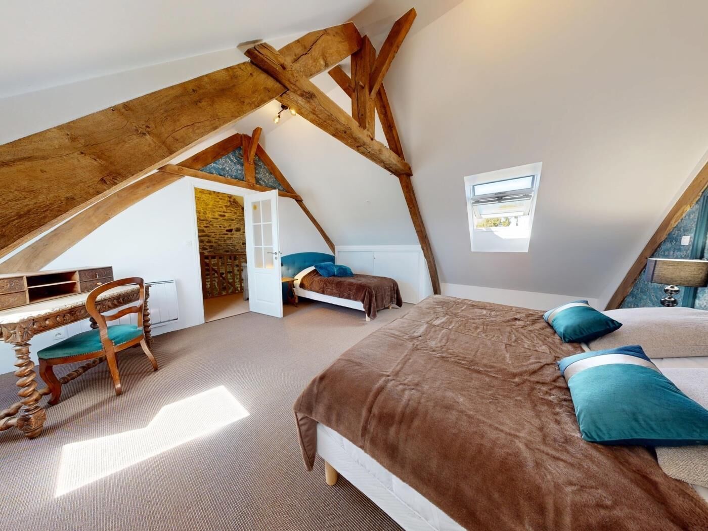 A bedroom with a sloped ceiling, a bed, a desk, and a chair.