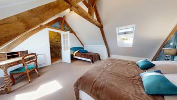 A bedroom with a sloped ceiling, a bed, a desk, and a chair.