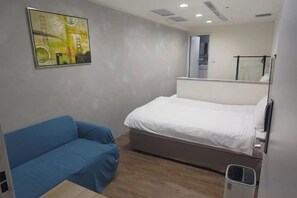 A bedroom with a bed, a blue sofa, a painting on the wall, and a window. - Happiness meworld (Taipei)