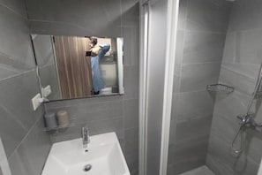 A bathroom with a white sink, a mirror, and a shower enclosure. - Happiness meworld (Taipei)