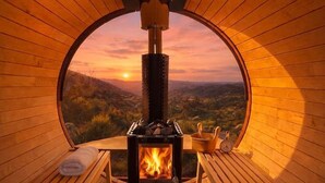 A circular wooden room with a wood-burning stove, benches, and a view of the landscape. - San Diego Serenity Hills, Pickleball, Golf, Infinity Pool with Epic Views (Jamul)