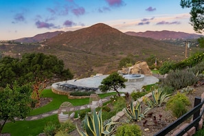 A landscaped garden with a pool, seating area, and a view of a mountain range.