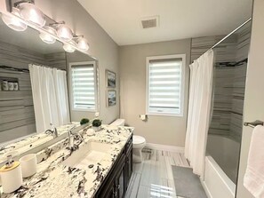 Une salle de bain moderne avec un meuble-lavabo à deux vasques, un grand miroir et une douche à l’italienne.