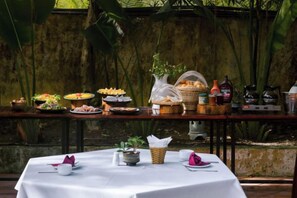 A buffet table with various food items and a small table with a vase and napkins. - Hoi An Phu Quoc Resort & Spa (Phu Quoc Island)