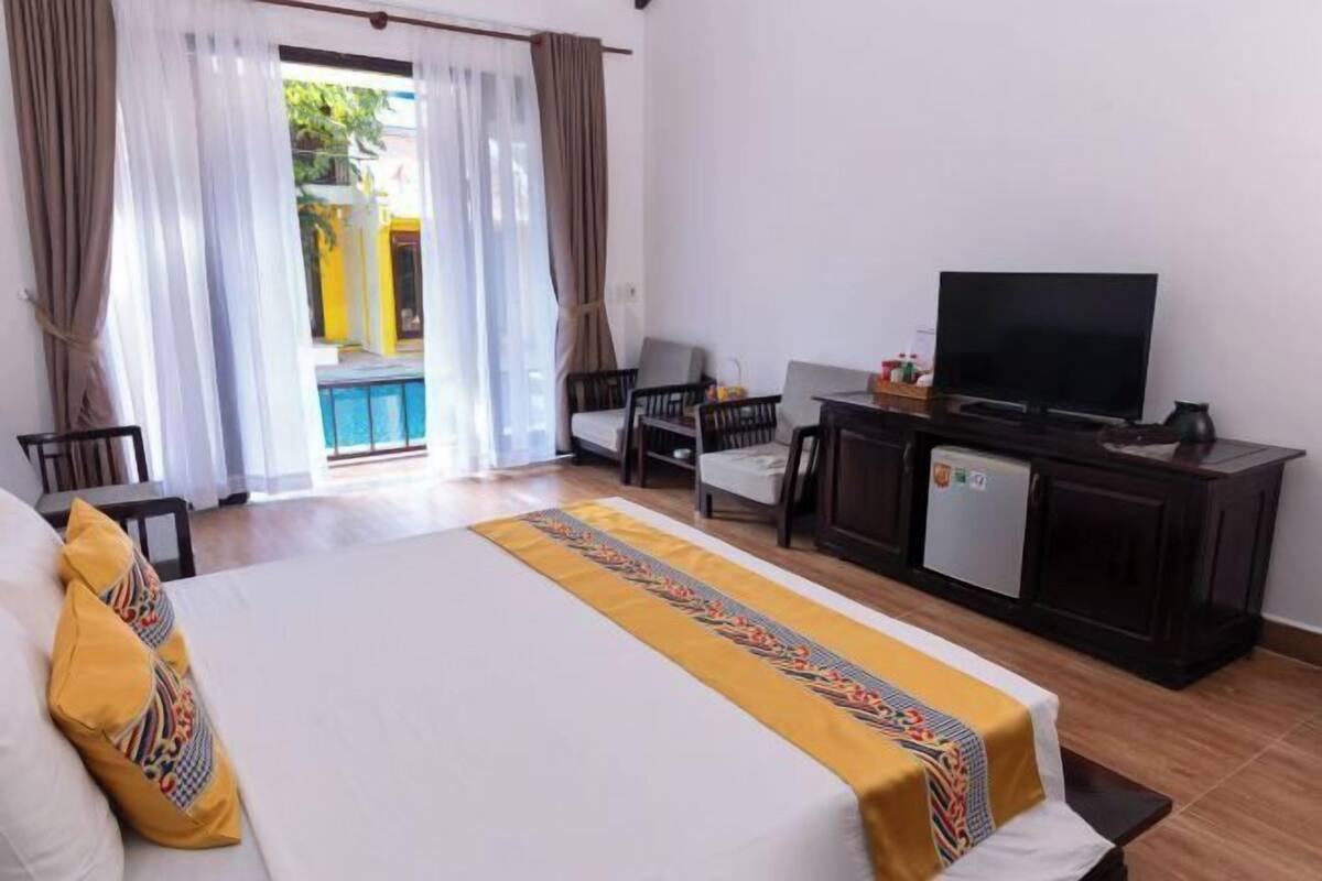 A hotel room with a bed, a TV, a desk, and a small refrigerator.