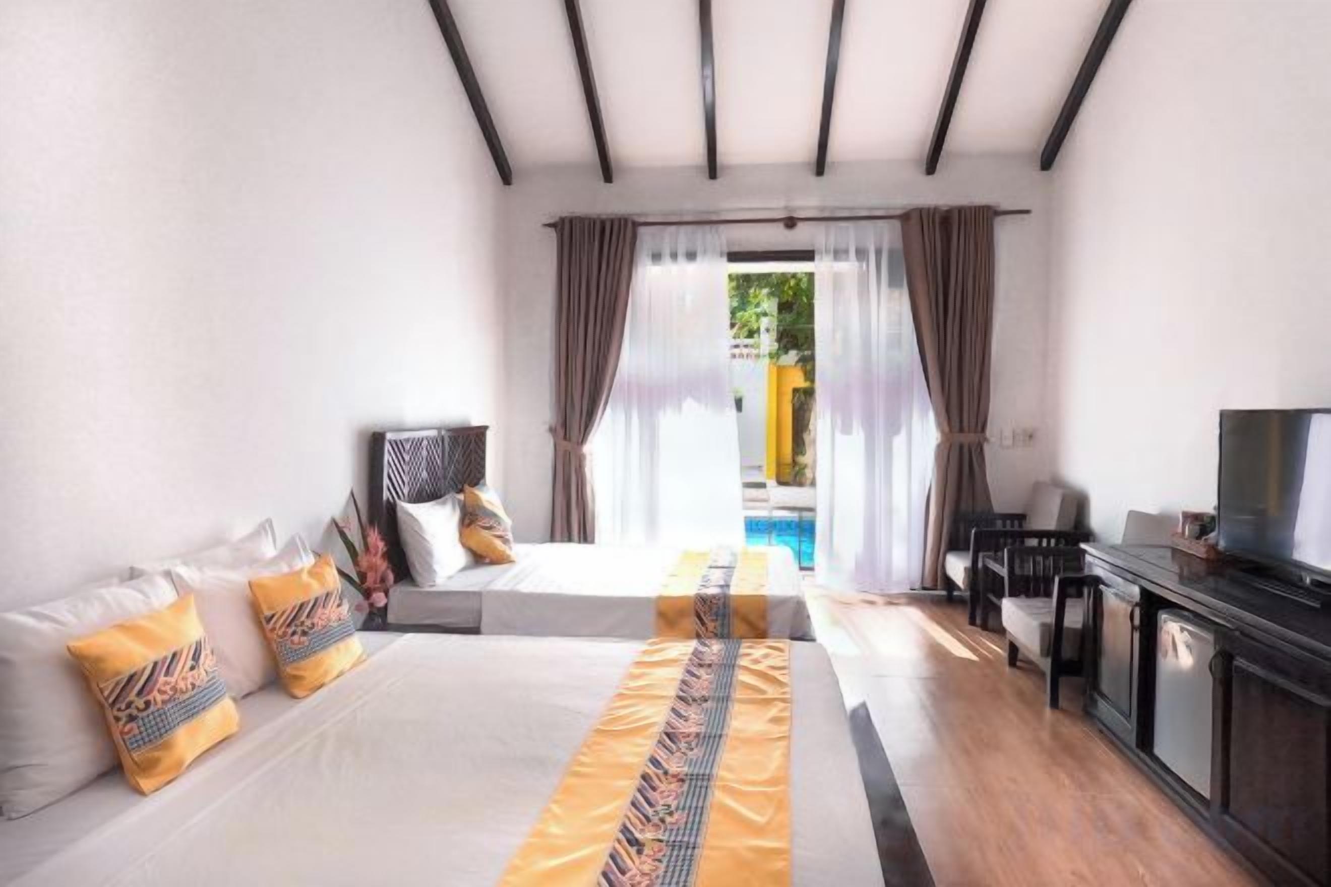 A hotel room with a bed, a TV, a desk, and a view of a swimming pool.