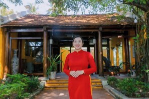 A woman standing in front of a building with a tiled roof and a covered entrance. - Hoi An Phu Quoc Resort & Spa (Phu Quoc Island)