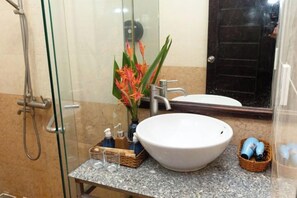 A bathroom with a glass shower enclosure, a white sink, and a mirror. - Hoi An Phu Quoc Resort & Spa (Phu Quoc Island)