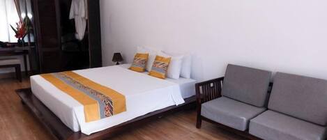 A hotel room with a bed, a sofa, a wardrobe, and a desk.