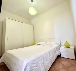 Un dormitorio con cama, mesita de noche, armario e iluminación colgante.