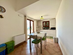 A compact kitchen with a dining table and chairs, a window with curtains, and a ceiling fan. - La Badia (Vico Equense)