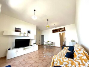 A living room with a TV, sofa, and dining area. - La Badia (Vico Equense)