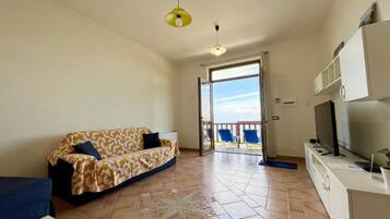 Appartamento Deluxe, vista mare | Area soggiorno | TV a schermo piatto 36 pollici con canali digitali