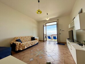 Appartamento Deluxe, vista mare | Area soggiorno | TV a schermo piatto 36 pollici con canali digitali