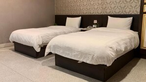 Ein Doppelbett mit dunklem Kopfteil, zwei Einzelbetten, ein Nachttisch und eine Wand mit Muster.