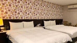 Ein Hotelzimmer mit zwei Betten, einer Wand mit Muster, einem Nachttisch mit Lampe und einem Sessel.