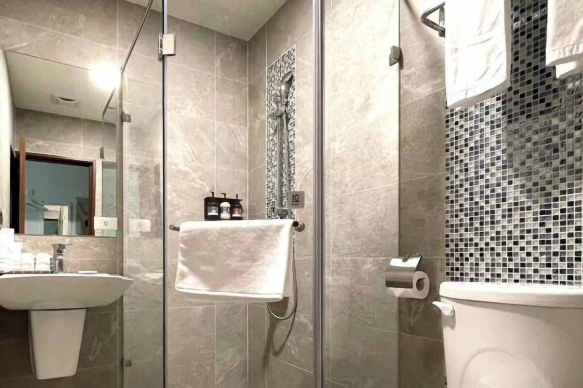 A modern bathroom with a glass shower enclosure, a white sink, and a toilet.