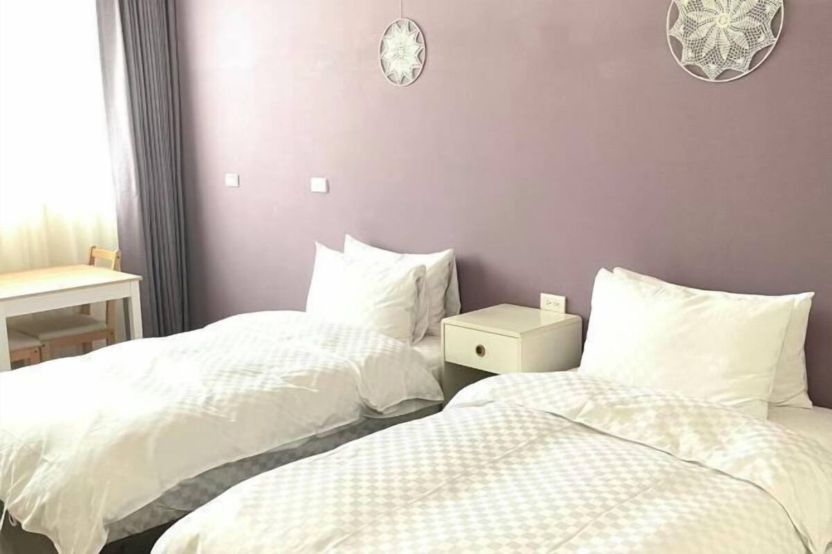 A room with two beds, a small table, and a nightstand.