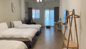 A hotel room with three beds, a wooden floor, a desk with a chair, and a television. - Chju Inn (Tainan)