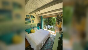 A bedroom with a bed, a window, and a view of the outdoors.