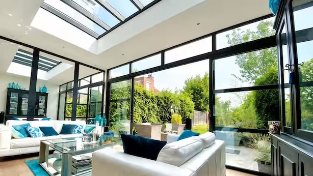 A modern living room with a glass ceiling, white sofa, and a glass coffee table.