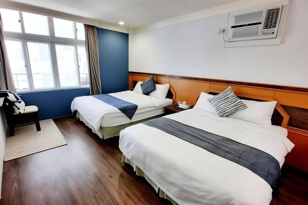 A hotel room with two beds, a desk, and a chair.