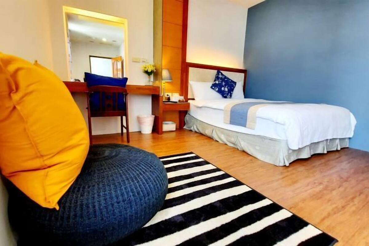 A bedroom with a bed, a desk, a chair, and a sofa.