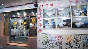 A hotel entrance with a glass door, a reception desk, and a wall with multiple rooms displayed. - 101 Hotel (Hsinchu)