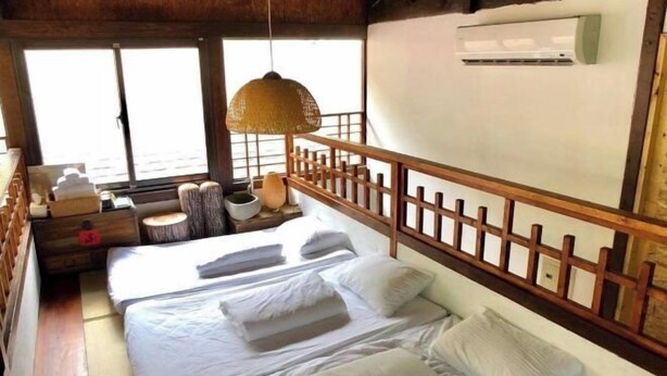 A room with a bed, a wooden headboard, a hanging lamp, a small table with a lamp, and a window with a view. - Soundwater (Miaoli)
